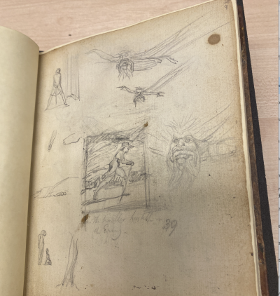 An old sketchbook page with pencil drawings of figures, faces, and a person riding a horse.