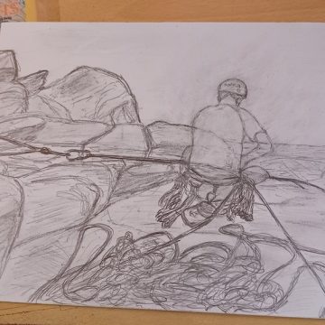 A pencil sketch shows a rock climber with ropes and gear from behind, placed on a wooden desk surrounded by art supplies.
